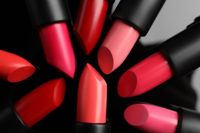 Many bright lipsticks on black glass surface, flat lay