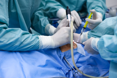 Photo of Professional doctors performing 
frontal sinus trephination in surgery room, closeup