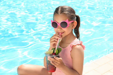 Girl with delicious refreshing drink near swimming pool