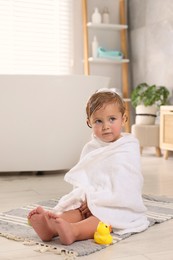 Photo of Cute little girl wrapped with towel after bath at home