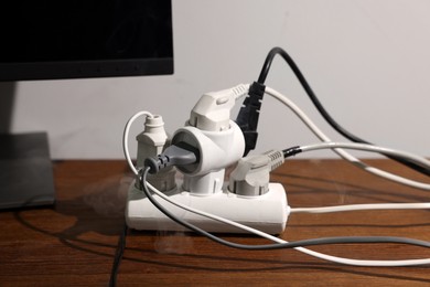 Photo of Smoking plug in power strip on wooden table. Electrical short circuit