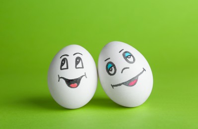 Eggs with drawn happy faces on green background