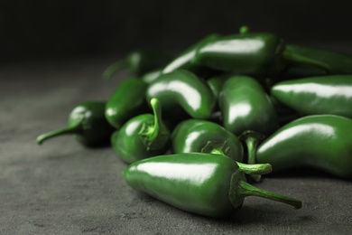 Pile of green hot chili peppers on grey table, closeup. Space for text