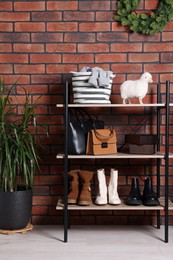 Photo of Modern shoe storage bench and potted plant near red brick wall in hallway. Interior design