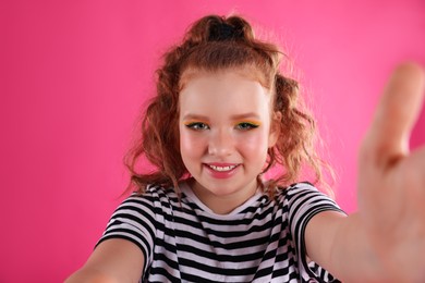 Cute indie girl taking selfie on pink background