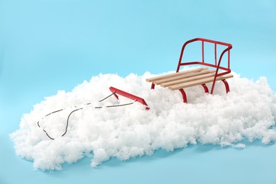 Empty sleigh in artificial snow on light blue background. Winter activity
