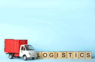 Toy truck and cubes with word LOGISTICS on light blue background, space for text. Wholesale concept