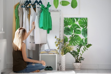 Photo of Young woman near clothes rack indoors. Stylish dressing room interior