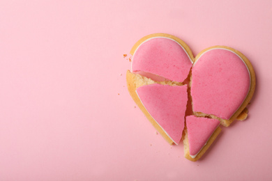 Broken heart shaped cookie on pink background, top view with space for text. Relationship problems concept