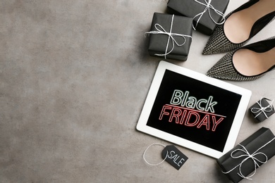 Tablet with Black Friday announcement, shoes and gifts on grey background, flat lay. Space for text