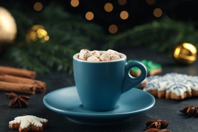 Photo of Delicious hot chocolate and Christmas decor on black table against blurred lights