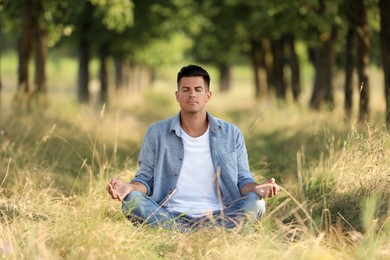 Man meditating in forest on sunny day