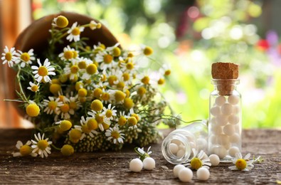 Bottles of homeopathic remedy and beautiful flowers on wooden table