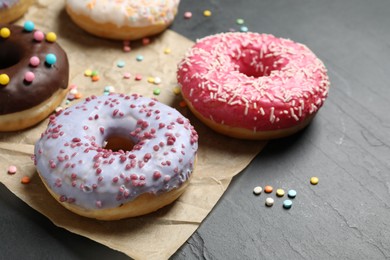 Photo of Yummy donuts with sprinkles on dark background, closeup
