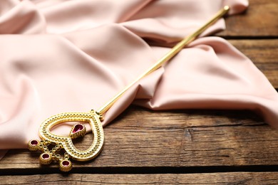 Beautiful golden magic wand and pink fabric on wooden table
