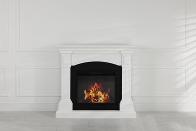 Photo of Modern electric fireplace near white wall in room