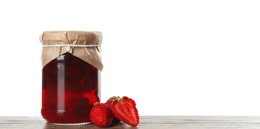 Glass jar of pickled strawberries on wooden table against white background. Space for text