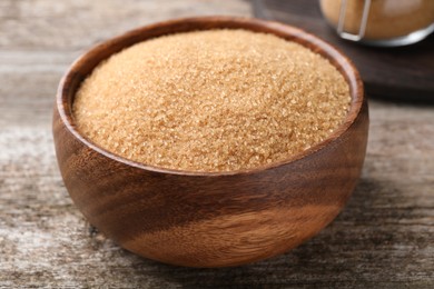 Brown sugar in bowl on wooden table, closeup