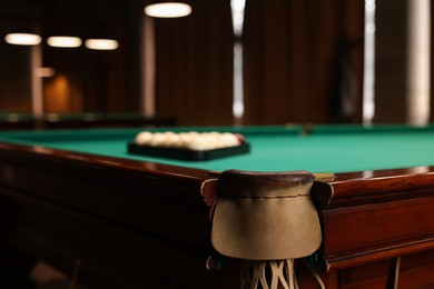 Photo of Balls in triangle rack on green table indoors, focus on billiard pocket. Space for text