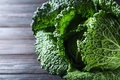 Photo of Fresh ripe savoy cabbage on black wooden table, closeup