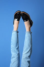 Woman wearing stylish shoes on blue background, closeup