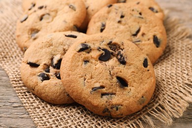 Photo of Delicious chocolate chip cookies on burlap fabric, closeup