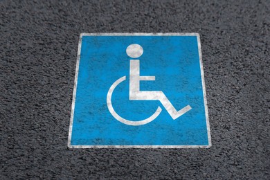 Wheelchair symbol on asphalt road, above view. Disabled parking permit