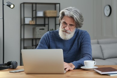 Middle aged man with laptop learning at table indoors