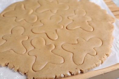 Photo of Making homemade Christmas cookies. Dough for gingerbread men on wooden board, closeup