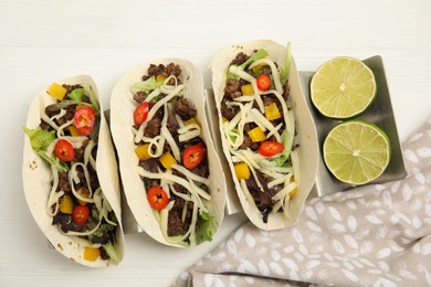 Delicious tacos with fried meat, vegetables and cheese on white wooden table, flat lay