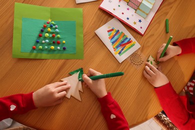 Little children making Christmas crafts at wooden table, top view
