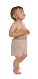 Cute baby in shorts learning to walk on white background