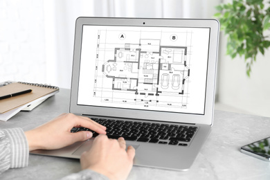 Architect making project of house on laptop in office, closeup