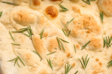 Traditional Italian focaccia bread with rosemary as background, closeup
