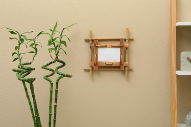 Green stems near beige wall with bamboo frame