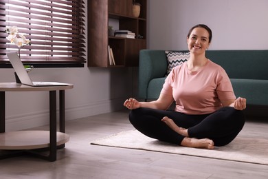 Overweight woman meditating on rug at home