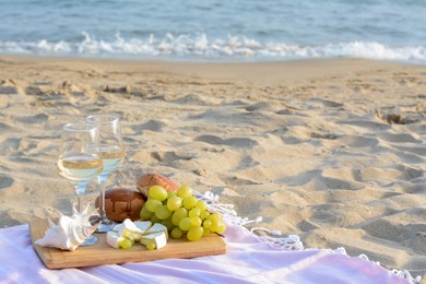 Glasses with white wine and snacks on sandy seashore. Space for text