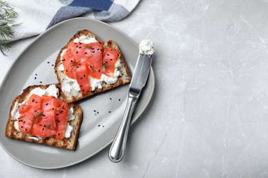 Delicious sandwiches with cream cheese, salmon and black sesame seeds served on light grey table, flat lay. Space for text