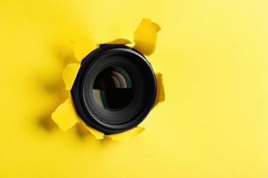 Hidden camera lens through torn in yellow paper