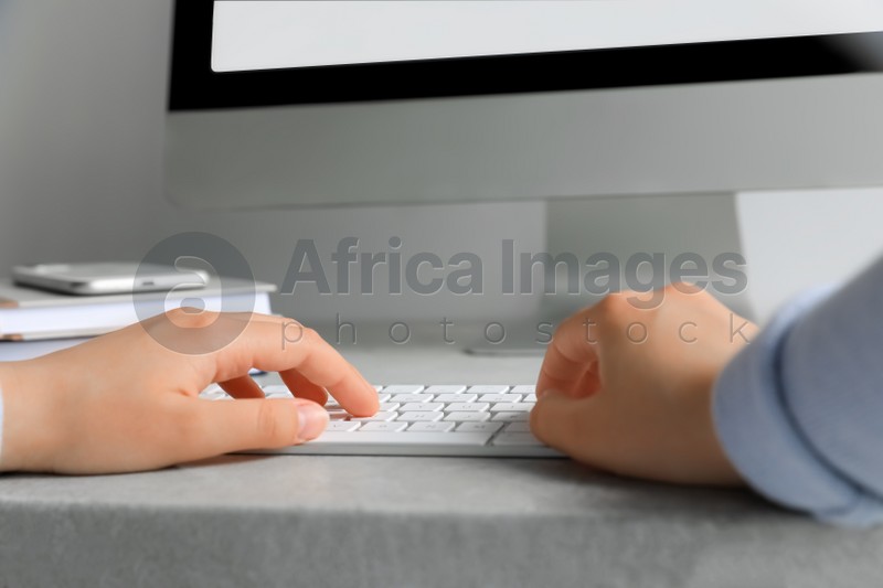 Woman working on modern computer at grey table, closeup