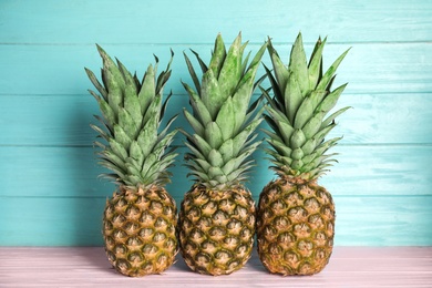 Photo of Fresh ripe juicy pineapples on pink wooden table