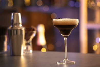 Glass of Espresso Martini on counter in bar, space for text. Alcohol cocktail