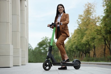 Businesswoman with modern electric kick scooter on city street