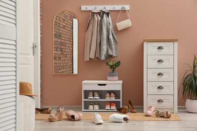 Stylish furniture and scattered shoes on floor in hall