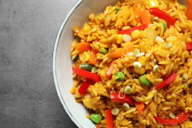 Delicious rice pilaf with vegetables on grey table