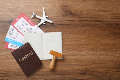 Flat lay composition with passports, stamp and flight tickets on wooden table, space for text