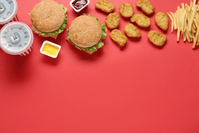 Flat lay composition with delicious fast food menu on red background. Space for text