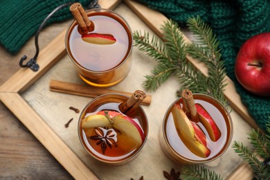 Hot mulled cider, ingredients and fir branches on wooden table, flat lay