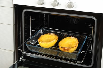 Baking dish with halves of cooked spaghetti squash in oven