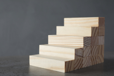 Steps made with wooden blocks on table against grey background. Career ladder